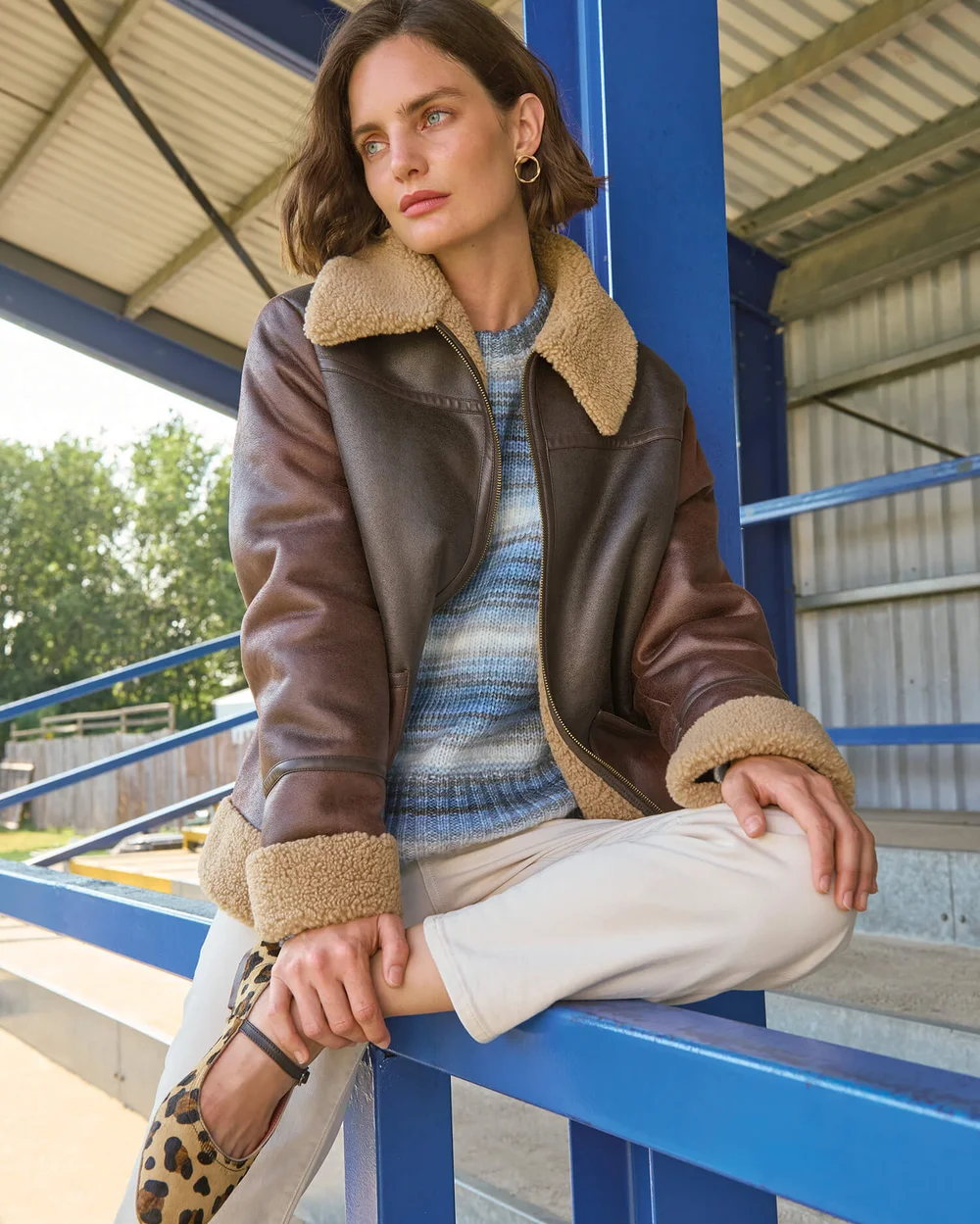 Frau in brauner Jacke mit blau gestreiftem Pullover und Leopardenmuster-Schuhen